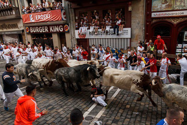 Man cowers in street during Running of the Bulls. Photo by AFP